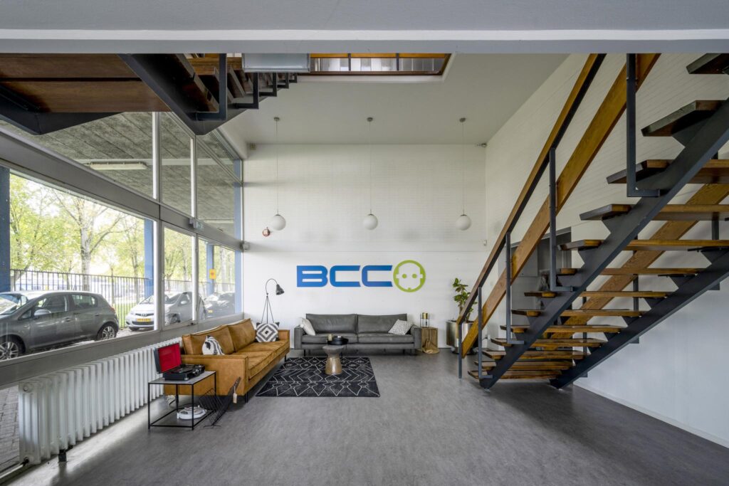 Modern lobby area of BCC Van der Madeweg with sofas, large windows, and a wooden staircase.